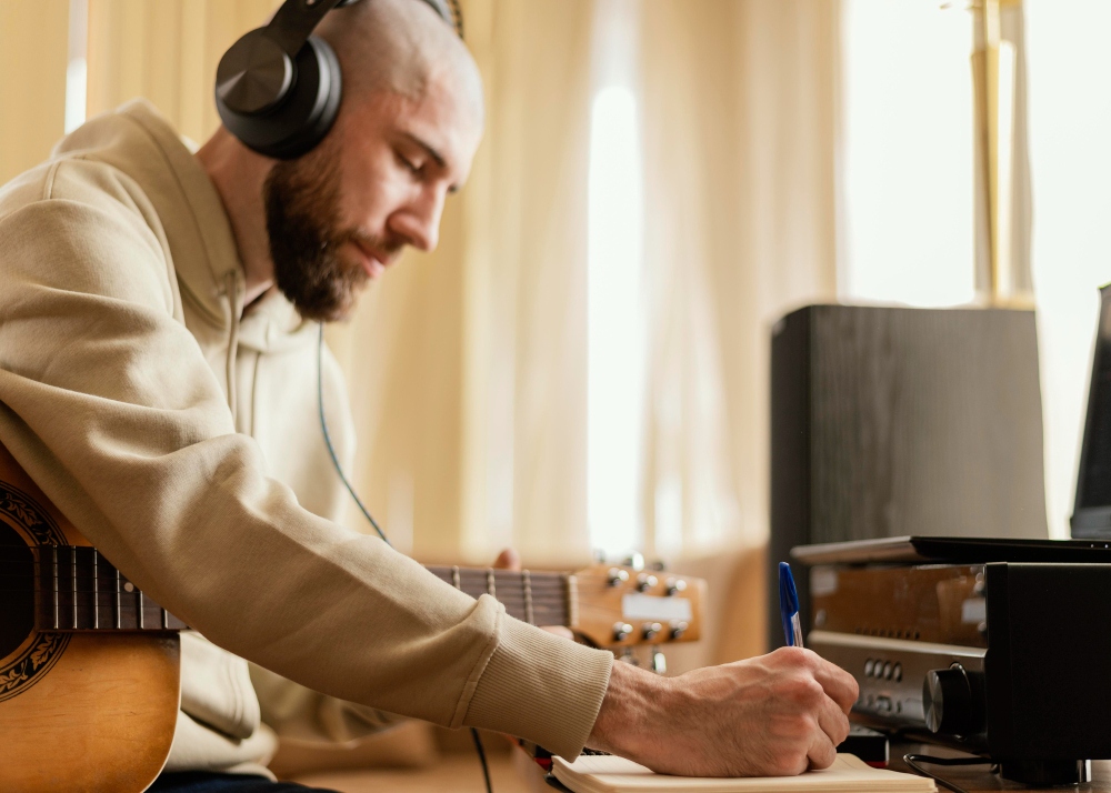 man with a guitar transcribing music manually