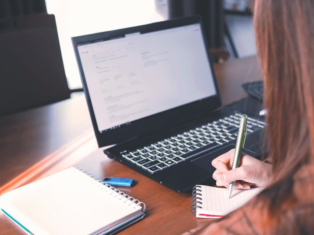 professional taking notes beside a laptop