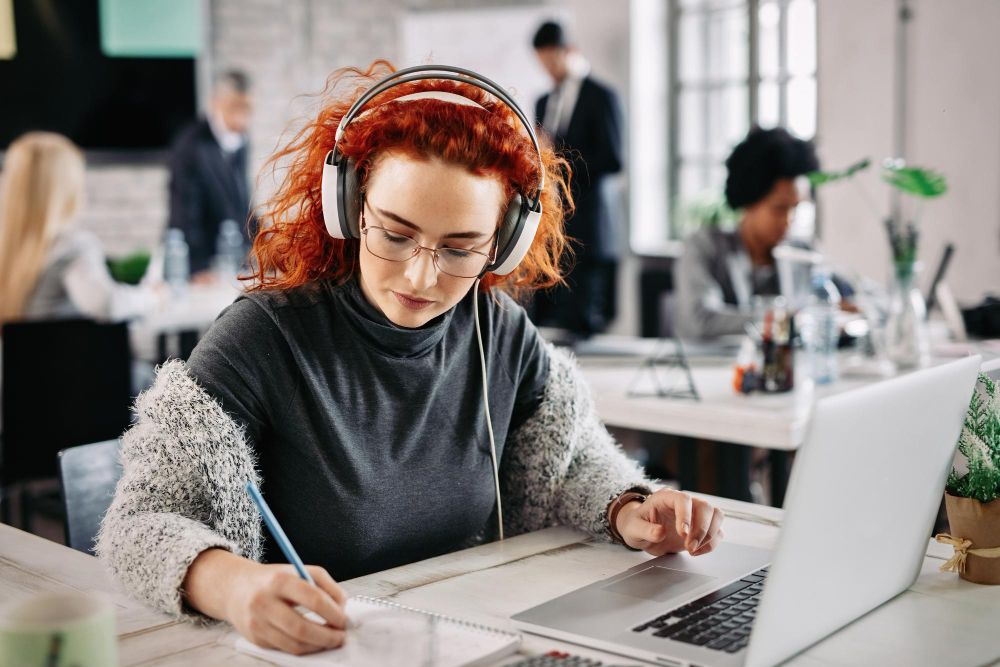 professional taking notes beside a laptop