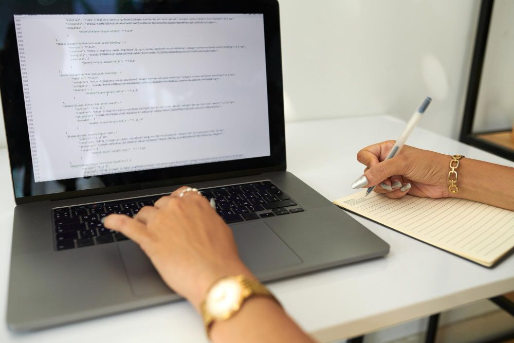 taking handwritten notes beside a laptop