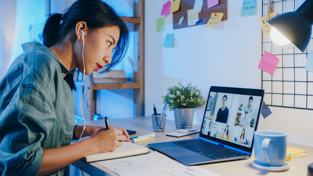 woman taking notes during video meeting