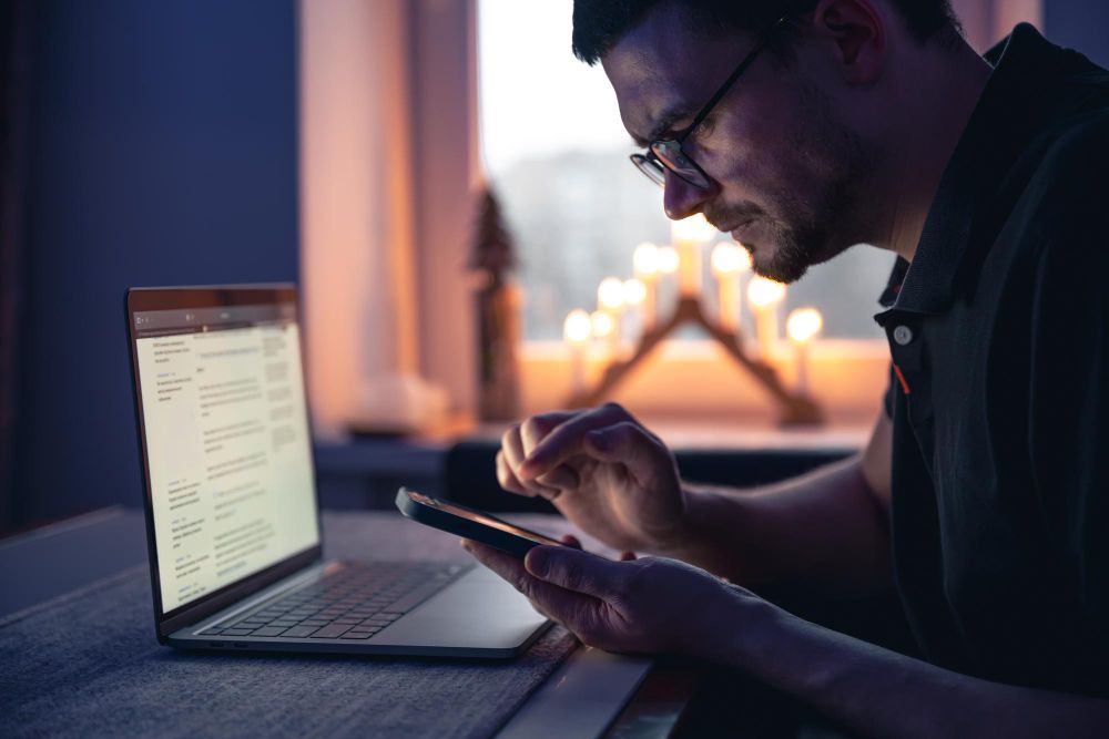 professional reviewing information on phone and laptop